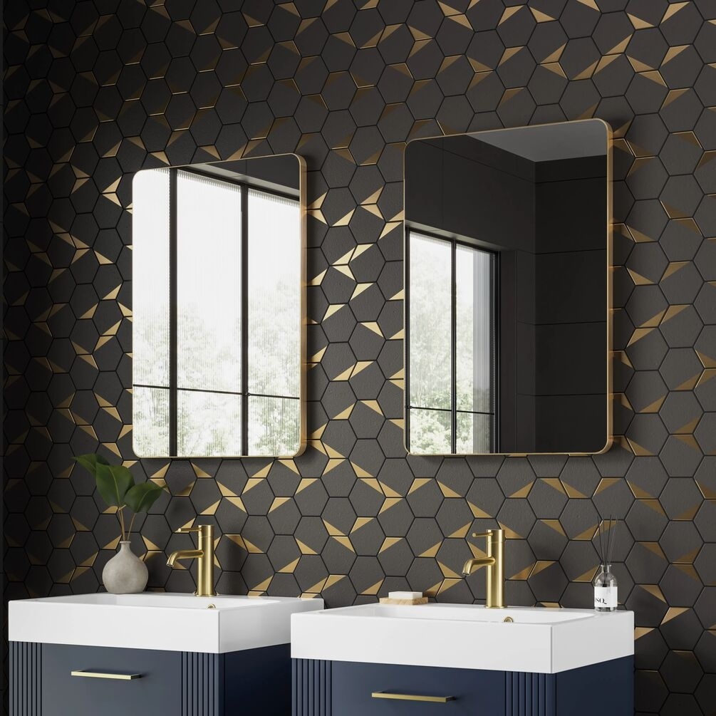 Lifestyle image of two hib. Trim Curve 400mm x 600mm Brushed Brass Bathroom Mirrors mounted side by side above two vanity units & basins